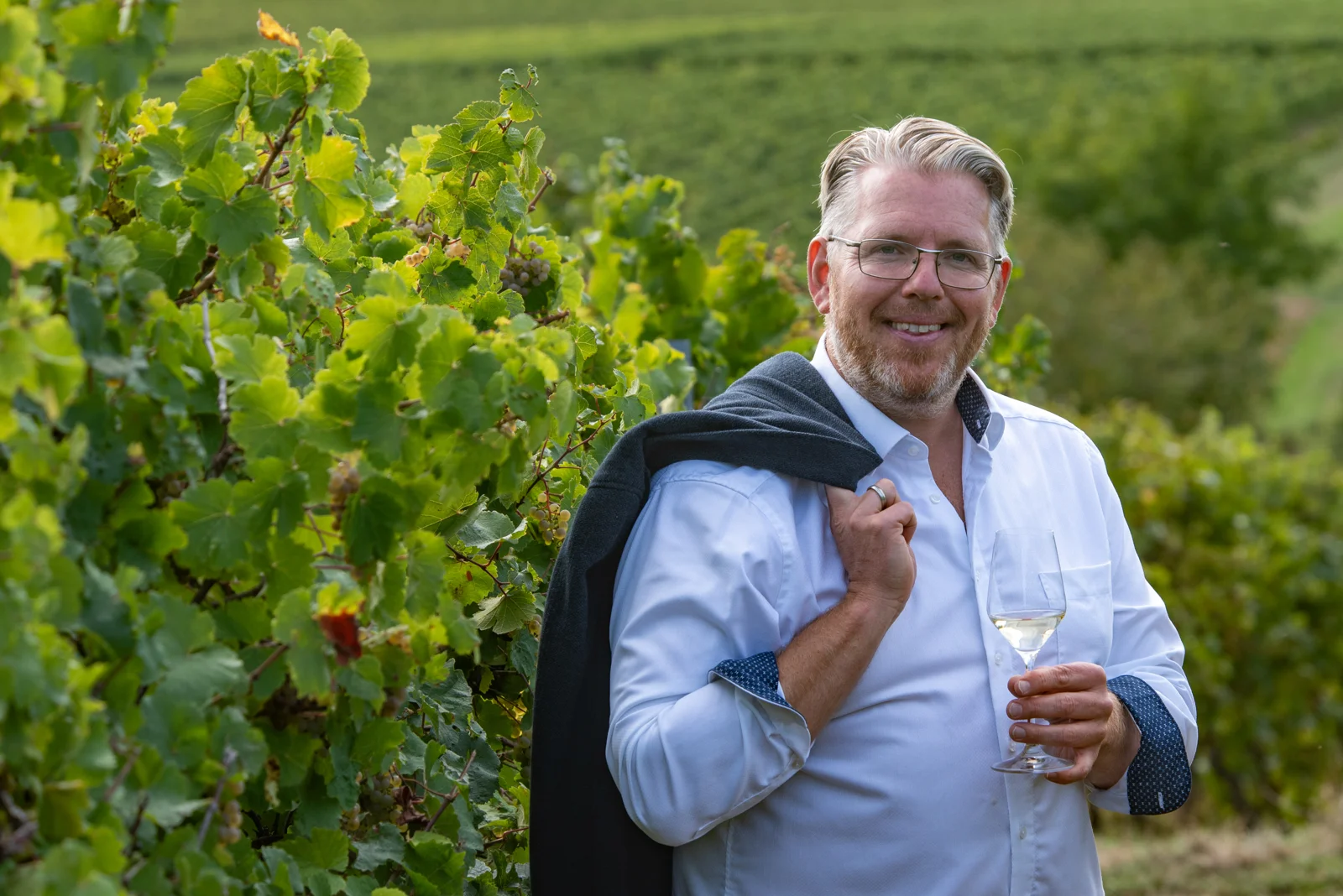 Benjamin Gillert mit dem Sakko über der Schulter im Weinberg